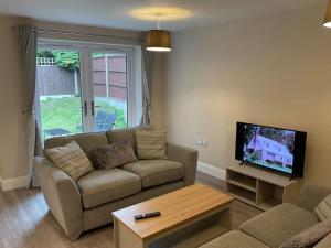 a living room with a couch and a flat screen tv at Beautiful Holiday Cottage in Ashbourne