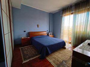 Dormitorio azul con cama y ventana en Casa di Frank: appartamento a due passi dal mare, en Cefalú