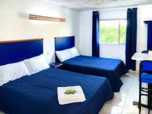 Habitación de hotel con 2 camas con sábanas azules en La Casa del Expositor, en Guadalajara