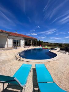 basen z niebieskimi krzesłami i dom w obiekcie Villa avec piscine privée w mieście Varès
