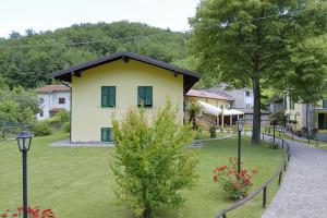 a yellow house in a yard with trees and flowers at Agriturismo Casa Castellini in Garbagna