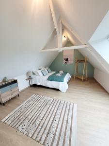 un dormitorio en el ático con una cama y una escalera en La Maison d'Equilly, en Équilly