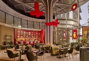 um restaurante com mesas e cadeiras e um bar em art'otel London Battersea Power Station, Powered by Radisson Hotels em Londres