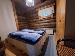 a bedroom with a bed in a wooden wall at Kelola Cottage in Keyritty +8 photos