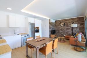 cocina y sala de estar con mesa de madera y sillas en Agaete Sunset Vista with jacuzzi 2-BR Apartment, en Puerto de las Nieves