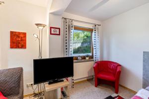 a living room with a flat screen tv and a red chair at An der Schwäbischen Alb in Mössingen