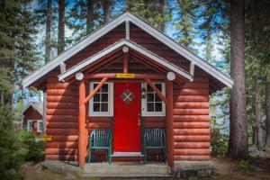 a log cabin with two chairs and a red door at Paradise Lodge and Bungalows in Lake Louise
