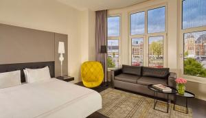 a hotel room with a bed and a couch and windows at Park Plaza Victoria Amsterdam in Amsterdam