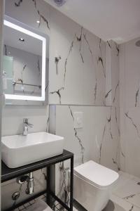 Baño blanco con lavabo y aseo en Hotel Vola, en Sarandë