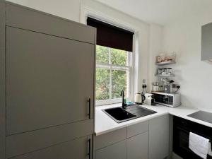 biała kuchnia ze zlewem i oknem w obiekcie Chic studio near Regent’s Park n8 w Londynie