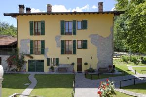 une grande maison jaune avec des fenêtres vertes à volets dans l'établissement Agriturismo Casa Castellini, à Garbagna