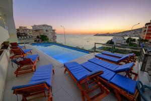 un grupo de sillas y una piscina con el océano en Hotel Vola, en Sarandë