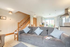 a living room with a gray couch and a staircase at Buttercup Cottage in Salisbury