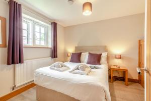 a bedroom with a large white bed with towels on it at Buttercup Cottage in Salisbury