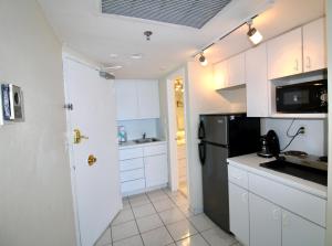 a kitchen with white cabinets and a black refrigerator at Oceanfront studio with ocean view, easy beach access and free parking! in Miami Beach