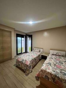 um quarto com 2 camas e uma grande janela em Appartements lux respectueux em Sidi Bouqnadel