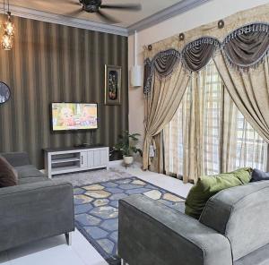 Sala de estar con 2 sofás y TV en Homestay Machang - Lycaste Inn Muslim, en Macang