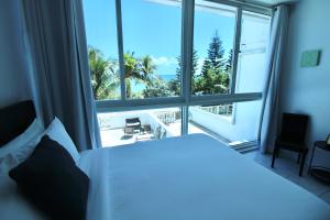 sypialnia z białym łóżkiem i dużym oknem w obiekcie Beachfront Townhouse with private patio, direct beach access, gym, bars & free parking! w Miami Beach