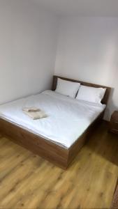 a bed with white sheets and pillows on a wooden floor at Popas Momaia in Curtea de Argeş