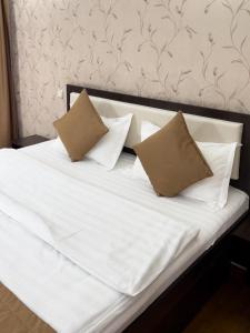 - un lit avec des draps blancs et 2 oreillers dans l'établissement Apartment 5, à Almaty