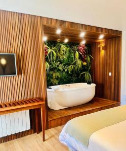 a bathroom with a bath tub with a plant mural at Pousada Dom Alfredo José in Campos do Jordão