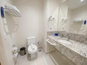 Hotel Rainha do Brasil في أباريسيدا: حمام ابيض مع مرحاض ومغسلة
