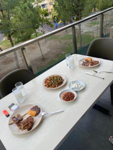 a white table with plates of food on it at Bornova nezih ferah Yıllık-Aylık_Haftalık in Burunabat