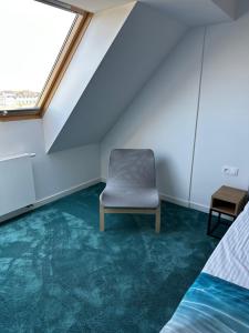 a chair in an attic room with green carpet at Apartments Deluxe SARBINOWO in Sarbinowo
