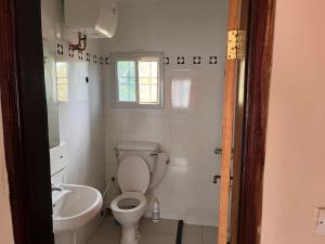 a white bathroom with a toilet and a sink at B&Y Holiday Apartments in Brusubi