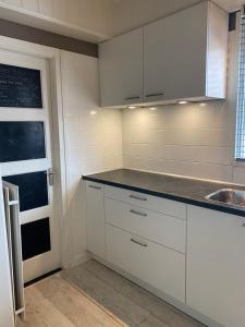 een keuken met witte kasten en een wastafel bij Free Fly Loft Drachten in Drachten