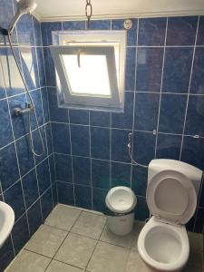 a blue tiled bathroom with a toilet and a window at Hotel Capu' Turcului in Eforie Sud
