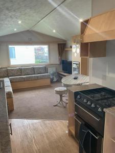 een keuken en een woonkamer met een bank en een fornuis bij Fantasy Island, Sunnymede 8 Berth in Ingoldmells