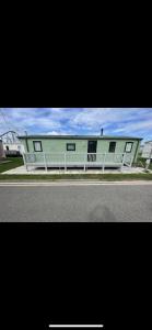 a green building with a white fence on the side of a road at Fantasy Island, Sunnymede 8 Berth in Ingoldmells