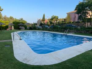 a swimming pool with blue water in a yard at Apartamento Green Golf Islantilla in Islantilla