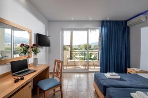 Habitación de hotel con cama y escritorio con ordenador portátil en Aeolos Beach Resort, en Malia