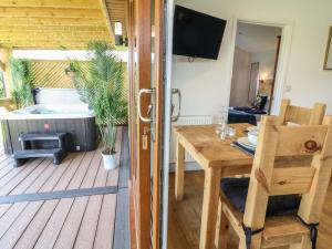 a room with a wooden deck with a table and a fireplace at Juniper in Swadlincote