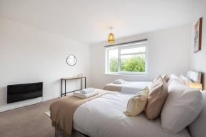 a white bedroom with two beds and a window at Admiral - 2 Bedroom Flat With Parking in Southampton