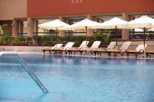 a hotel swimming pool with chairs and umbrellas at Hilton Alexandria Green Plaza in Alexandria