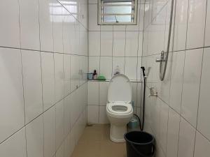 a white bathroom with a toilet and a window at Padang Besar Homestay Firdaus in Padang Besar