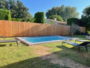 a backyard with a swimming pool and a wooden fence at Villa 100m2 Piscine 6 personnes in Châteauneuf-de-Gadagne