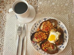 a plate of food with eggs and beans and a cup of coffee at Exotic Backpackers in Banyuwedang
