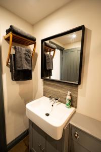 ein Bad mit einem Waschbecken und einem Spiegel in der Unterkunft Worfe View Cottage 