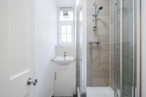 La salle de bains blanche est pourvue d'une douche et d'un lavabo. dans l'établissement APlaceToStay Central London Apartment, Zone 1 COV, à Londres