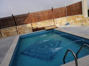 a swimming pool with blue water and a wooden fence at North Jewel 2023 in Ajloun
