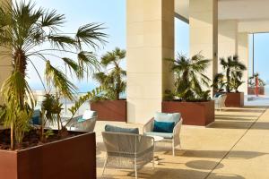 un hall avec des palmiers et des chaises dans l'établissement Hilton Garden Inn Bahrain Bay, à Manama