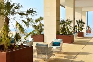 a hotel lobby with palm trees and chairs at Hilton Garden Inn Bahrain Bay in Manama