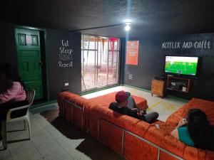 a group of people sitting on a couch watching tv at Hostel Plantas y Blanco in Baños