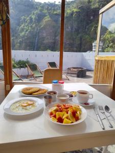 a table with plates of food and coffee on it at Hostel Plantas y Blanco in Baños
