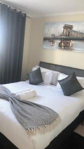 1 cama grande con sábanas y almohadas blancas en Menlyn Place Staycation, en Pretoria