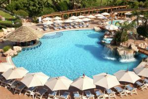 uma vista sobre uma piscina com guarda-sóis e cadeiras em Hilton Pyramids Golf em Cidade 6 de Outubro